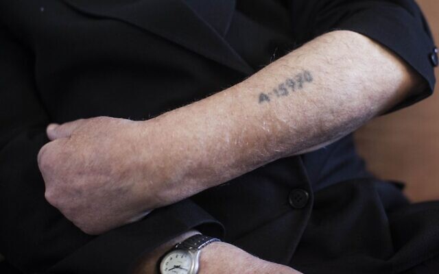 Un survivant de la Shoah montre son numéro de prisonnier tatoué sur son bras. (Crédit :  Yonatan Sindel/Flash90)