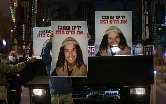 Des manifestants montrent des affiches à l’effigie d’Ahuvia Sandak, mort dans un accident de voiture lors d'une poursuite policière la semaine dernière, devant le siège de la police nationale à Jérusalem, le 26 décembre 2020. (Crédit : Yonatan Sindel / Flash90)