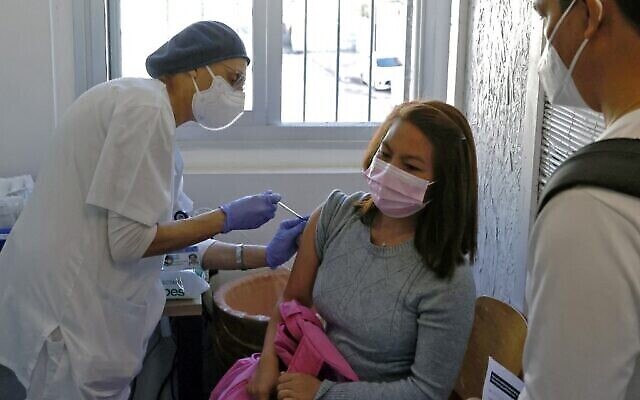 Une résidente étrangère  se fait vacciner contre la  COVID-19 au centre médical Sourasky de Tel Aviv pendant une campagne de vaccination des ressortissants et des réfugiés étrangers , le 9 février 2021. (Crédit :  JACK GUEZ / AFP)