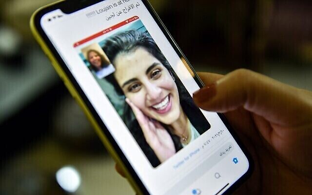 Cette photo prise le 10 février 2021 à Ryad, la capitale de l'Arabie saoudite, montre une femme regardant un tweet publié par la sœur de l'activiste saoudien Loujain al-Hathloul, Lina, montrant une capture d'écran d'eux ayant un appel vidéo après la libération de Hathloul après près de trois ans de détention. (Crédit : Fayez Nureldine / AFP)