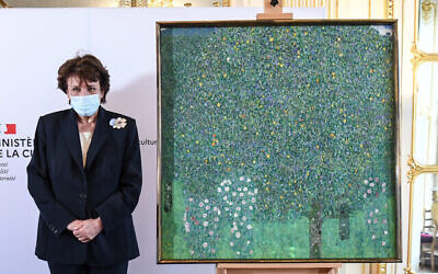 La ministre française de la Culture, Roselyne Bachelot, pose à côté d'une peinture à l'huile de Gustav Klimt peinte en 1905 intitulée "Rosiers sous les arbres", lors d'une cérémonie de restitution au musée d'Orsay à Paris, le 15 mars 2021. (Crédit : Alain Jocard / Pool Photo via AP)
