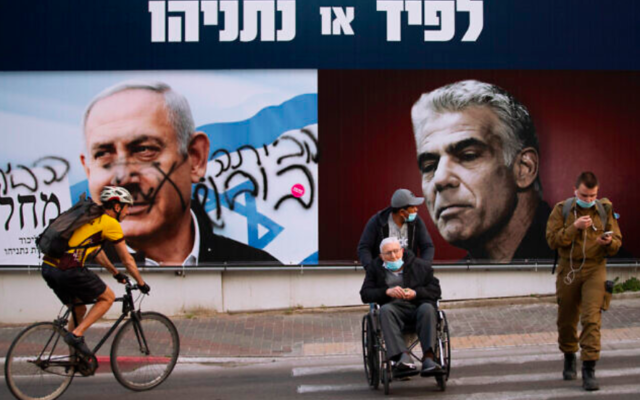 Un panneau d'affichage de campagne électorale pour le Likud qui montre un portrait de son chef, le Premier ministre Benjamin Netanyahu, à gauche, et du chef de l'opposition Yair Lapid. Le portrait de Netanyahu est dégradé par l'hébreu qui dit « rentre chez toi » à Ramat Gan, en Israël, dimanche 21 mars 2021. (Crédit : AP / Oded Balilty)