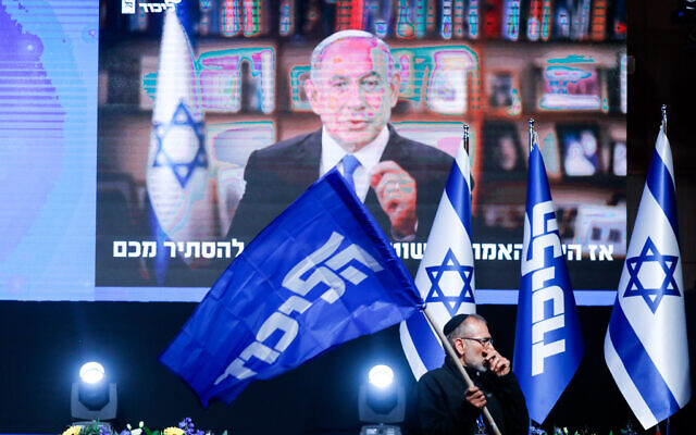 Un partisan du Likud devant une vidéo de Benjamin Netanyahu lors d'un événement du parti, à Jérusalem, le 23 mars 2021. (Crédit : Olivier Fitoussi/Flash90)