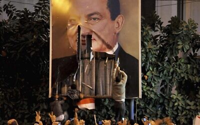 Des manifestants dégradent une affiche du président égyptien Hosni Moubarak à Alexandrie, en Égypte, le 25 janvier 2011. (Crédit : AP)