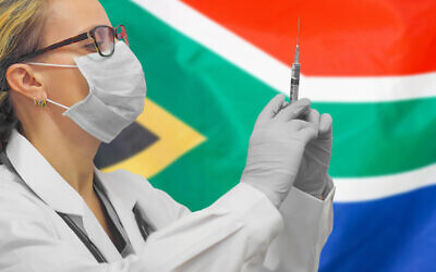 Une femme médecin avec une seringue devant un drapeau sud-africain. (Crédit :  Igor Vershinsky via iStock by Getty Images)