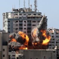 Le feu et la fumée montent de la tour Jala alors qu'elle est détruite lors d'une frappe aérienne israélienne après que Tsahal a averti les occupants de partir, à Gaza city, le 15 mai 2021 (Crédit : MAHMUD HAMS / AFP)