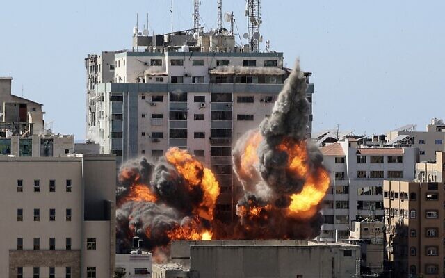 Le feu et la fumée montent de la tour Jalaa alors qu'elle est détruite lors d'une frappe aérienne israélienne après que Tsahal a averti les occupants de partir, à Gaza city, le 15 mai 2021 (Crédit : MAHMUD HAMS / AFP)