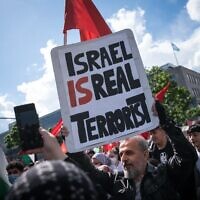 Un manifestant tient une pancarte où l'on peut lire "Israël est un vrai terroriste", le 15 mai 2021 sur la Hermannplatz à Berlin. (Crédit : STEFANIE LOOS / AFP)