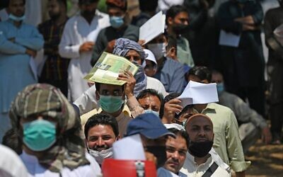 Des ressortissants pakistanais, portant des masques, font la queue pour demander un visa à l'ambassade d'Afghanistan à Islamabad, le 19 mai 2021. L'Afghanistan connaît un afflux improbable de visiteurs en raison de la pandémie de coronavirus. Des milliers de travailleurs pakistanais désespérés transitent par la capitale déchirée par la guerre pour tenter de rejoindre l'Arabie saoudite. (Crédit : Aamir QURESHI / AFP)