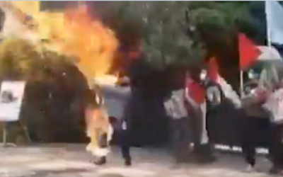 Capture d'écran d'une vidéo partagée sur les médias sociaux montrant un homme en Iran tenant un drapeau israélien géant auquel on a mis le feu, avant que les flammes ne le brûlent lui-même. (Twitter)