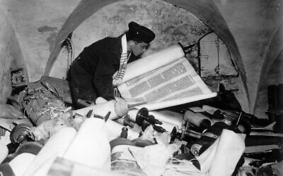 Illustration : Après la capitulation de l'Allemagne nazie, l'aumônier Samuel Blinder dans la cave de l'ancien Institut des sciences raciales à Francfort, le 6 juillet 1945. Debout, au milieu d'une collection de manuscrits et de livres provenant de tous les pays d'Europe occupés par les nazis, il examine l'un des centaines de rouleaux de la Torah. (Crédit : AP)