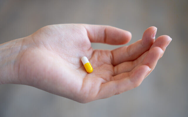 Illustration : une pilule est tenue dans une main (Crédit : Rosifan19; iStock by Getty Images)