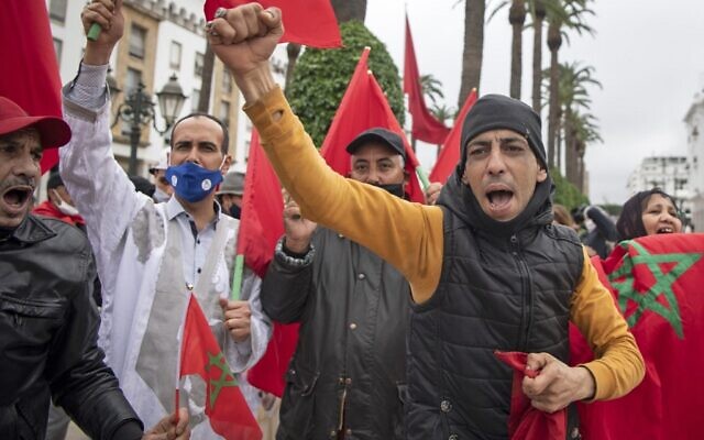 Les Marocains se réjouissent devant le parlement de Rabat après l'adoption par les États-Unis d'une nouvelle carte officielle du Maroc incluant les territoires disputés du Sahara occidental, le 13 décembre 2020. (Crédit : Fadel Senna/AFP)