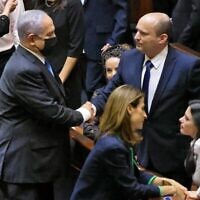 Le premier ministre israélien sortant Benjamin Netanyahu, à gauche, serre la main de son successeur, le nouveau premier ministre Naftali Bennett, après une session spéciale pour voter sur un nouveau gouvernement à la Knesset à Jérusalem, le 13 juin 2021. (Emmanuel Dunand / AFP)