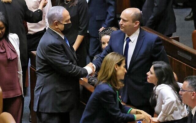 Le premier ministre israélien sortant Benjamin Netanyahu, à gauche, serre la main de son successeur, le nouveau premier ministre Naftali Bennett, après une session spéciale pour voter sur un nouveau gouvernement à la Knesset à Jérusalem, le 13 juin 2021. (Emmanuel Dunand / AFP)