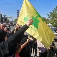 Des Libanais brandissent un drapeau du Hezbollah alors que des pétroliers transportant du carburant iranien arrivent de Syrie à al-Ain, dans la vallée de la Bekaa, à l'est du Liban, le 16 septembre 2021. (Crédit : AFP)