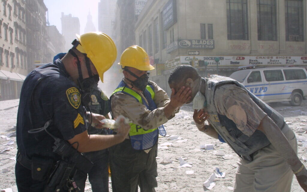 Des policiers aident à rincer les yeux d'un homme après la chute des tours jumelles, le 11 septembre 2001, à New York. (AP Photo/Shawn Baldwin)