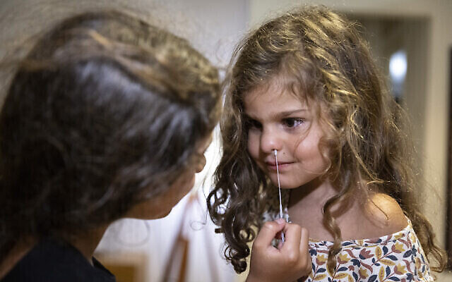 Une fillette réalise un test de dépistage antigénique au coronavirus sur sa sœur à l'aide d'un test rapide avant la rentrée scolaire, à Jérusalem, le 1er août 2021. (Crédit : Olivier Fitoussi/Flash90)