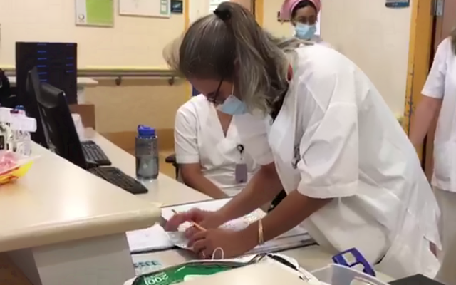 Le personnel hospitalier de l'hôpital Hillel Yaffe enregistre les données des patients à l'aide d'un stylo et de papier, suite à une cyberattaque par rançongiciel, le 13 octobre 2021. (Crédit :  hôpital Hillel Yaffe)