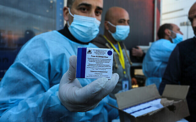 Des Palestiniens du ministère de la Santé reçoivent une cargaison de doses de vaccin russe contre le coronavirus Sputnik V envoyée par les Émirats arabes unis, après que les autorités égyptiennes ont autorisé l'entrée à Gaza par le passage de Rafah, dans le sud de la bande de Gaza, le 21 février 2021. (Crédit : Abed Rahim Khatib/Flash90)