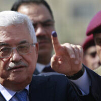 Sur cette photo d'archives du 20 octobre 2012, le président de l'Autorité palestinienne Mahmoud Abbas montre son doigt taché d'encre après avoir voté lors des élections locales, dans un bureau de vote de la ville de Ramallah, en Cisjordanie. (Crédit : AP Photo/Majdi Mohammed, Dossier)