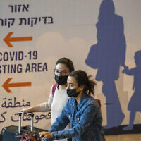 Des voyageurs portant le masque arrivent à l'aéroport Ben-Gurion après qu'Israël a interdit l'entrée des ressortissants étrangers pour contrer l'apparition d'un nouveau variant du coronavirus, le 28 novembre 2021. (Crédit : AP Photo/Ariel Schalit)