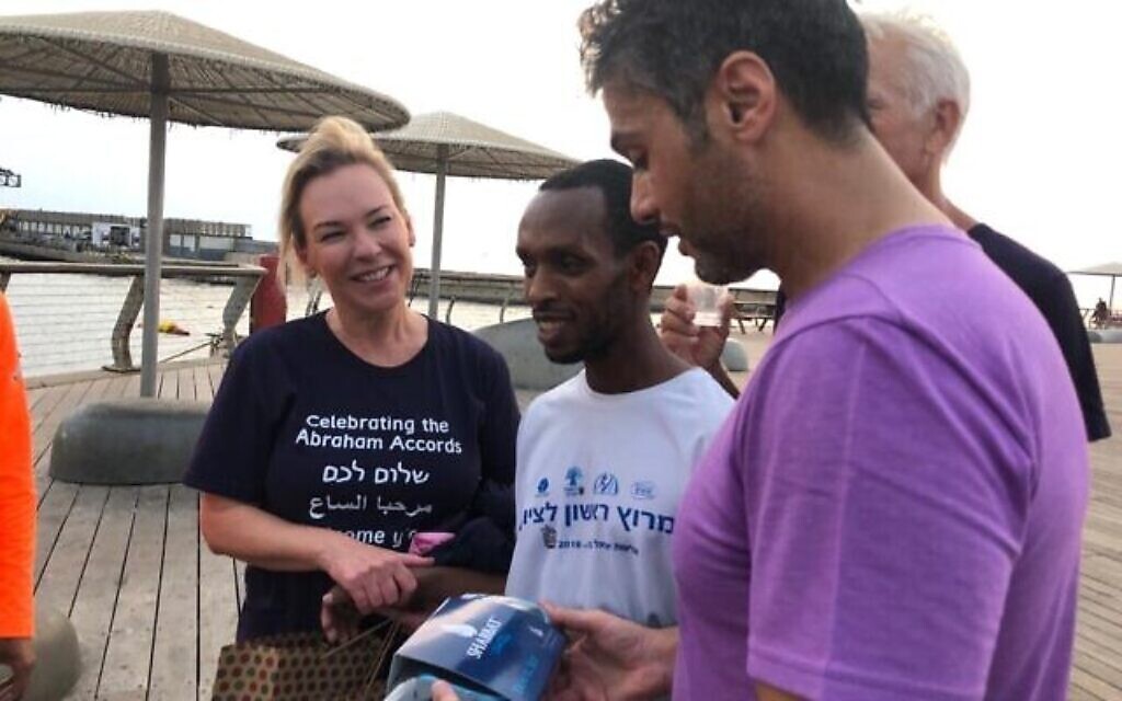 L'ambassadeur des Émirats arabes unis en Israël, Mohamed al Khaja (à droite), reçoit en cadeau un kit de voyage pour le Shabbat de la part du coureur israélien aveugle Avi Solomon (au centre), après leur course à Tel Aviv, le 18 novembre 2021 (Lazar Berman/Times of Israel).