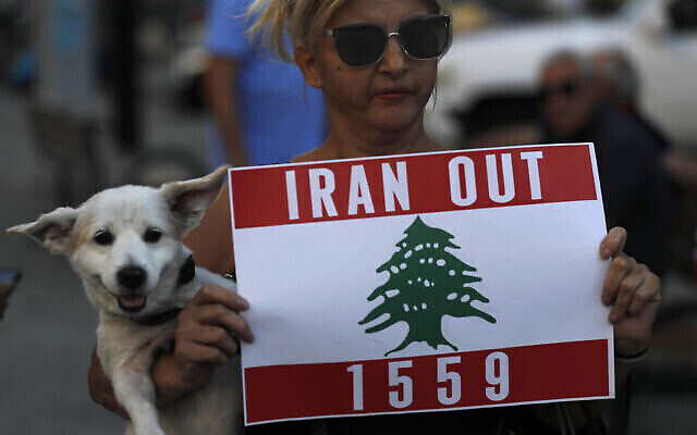 Une manifestante libanaise porte son chien et tient une pancarte lors d'une manifestation contre le groupe terroriste Hezbollah et la visite du ministre iranien des Affaires étrangères Hossein Amir-Abdollahian, Beyrouth, Liban, 6 octobre 2021. (AP Photo/Hussein Malla)