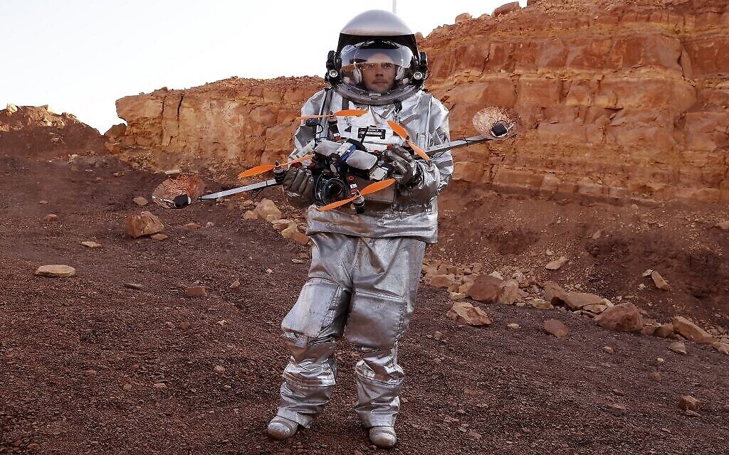 Un astronaute d'une équipe d'Europe et d'Israël et vêtu d'une combinaison spatiale tient un drone quadcopter lors d'une mission d'entraînement pour la planète Mars sur un site qui simule une station hors site au cratère Ramon à Mitzpe Ramon dans le sud du désert du Néguev en Israël, le 10 octobre 2021. (Photo par JACK GUEZ / AFP)