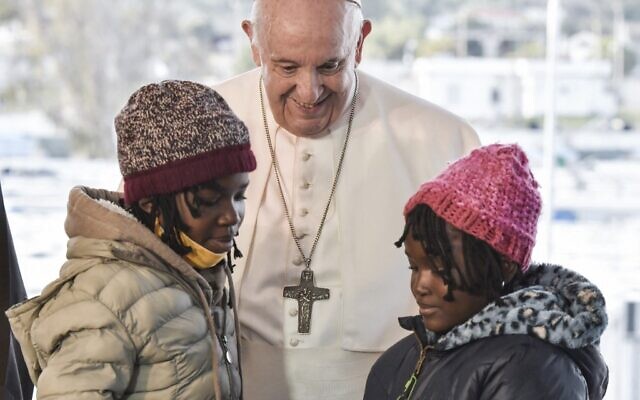 Le pape François salue deux jeunes réfugiées au centre d'accueil et d'identification (RIC) de Mytilène, sur l'île de Lesbos, le 5 décembre 2021. (Crédit : Louisa GOULIAMAKI / POOL / AFP)