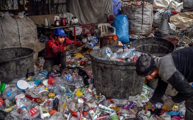 Des réfugiés afghans ramassent des déchets dans une décharge, le 18 novembre 2021, à Istanbul. (Crédit : Bulent KILIC / AFP)