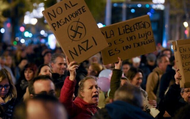 Des manifestants brandissent des pancartes indiquant "la liberté n'est pas un luxe, c'est un droit", "non au passeport nazi" lors d'une manifestation contre le laissez-passer sanitaire Covid-19, avec lequel les autorités visent à limiter la propagation de la pandémie de Covid-19, à Barcelone, le 11 décembre 2021. (Crédit : LLUIS GENE / AFP)