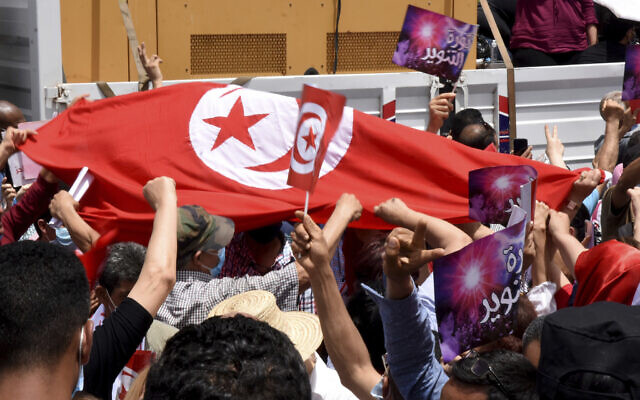 Photo d'illustration : Des manifestants brandissent le drapeau tunisien pendant une manifestation à Tunis, le 5 juin 2021. (Crédit : AP Photo/Hassene Dridi)