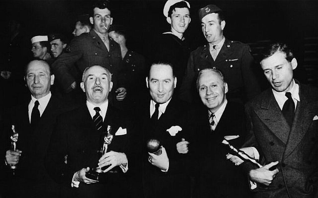 Lauréats de "Casablanca" : un Michael Curtiz endormi, Jack Warner (qui parle, comme d'habitude), Hal Wallis (avec son prix Thalberg), l'un des hôtes de l'événement, Jack Benny, et le scénariste Howard Koch. (Crédit : autorisation/collection de l'auteur)