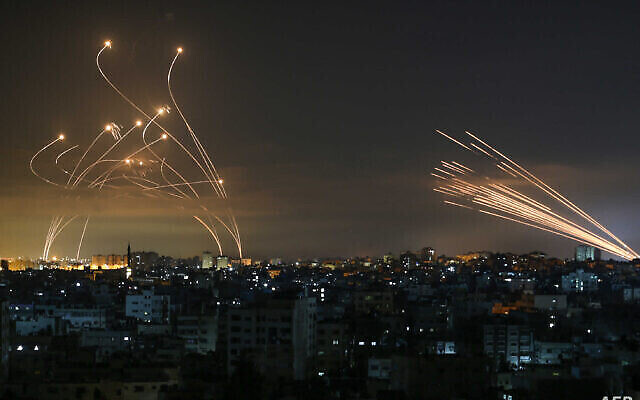 Des roquettes en provenance de Gaza, à droite, sont vues dans le ciel nocturne tirées en direction d'Israël depuis Beit Lahia, dans le nord de la bande de Gaza, le 14 mai 2021, tandis que des missiles d'interception  Dome de Fer, à gauche, se dressent à leur rencontre. (Crédit : Anas Baba/AFP)