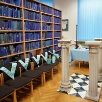 Des colliers maçonniques à côté d'étagères de livres à la bibliothèque universitaire de Poznan, qui abrite des archives historiques de la franc-maçonnerie en Europe amassées par les nazis, à Poznan, dans l'ouest de la Pologne, le 22 décembre 2021. (Crédit : JANEK SKARZYNSKI / AFP)