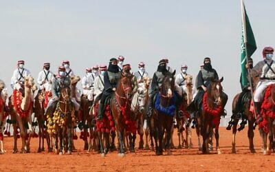 Des chameliers et des cavalières saoudiens participent à un défilé lors de la sixième édition du festival du chameau du roi Abdulaziz dans la région de Rumah, à quelque 161 km à l'est de la capitale Riyad, le 8 janvier 2022. (Crédit : Fayez Nureldine / AFP)