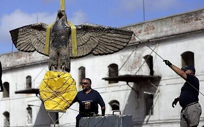 Des ouvriers observent la récupération d'un aigle du cuirassé allemand de la Seconde Guerre mondiale Graf Spee à Montevideo, en Uruguay, le 10 février 2006 (Crédit : Marcelo Hernandez/AP)