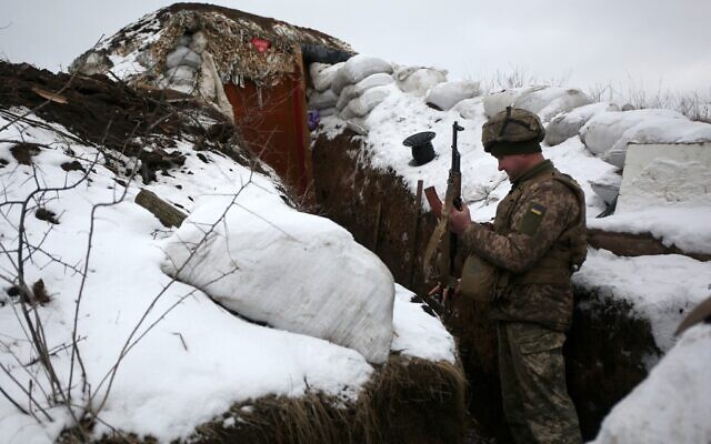 Un soldat des forces militaires ukrainiennes vérifie son arme dans une tranchée sur la ligne de front avec les séparatistes soutenus par la Russie, près du village de Zolote, dans la région orientale de Lougansk, le 21 janvier 2022 (Crédit : Anatolii STEPANOV / AFP).