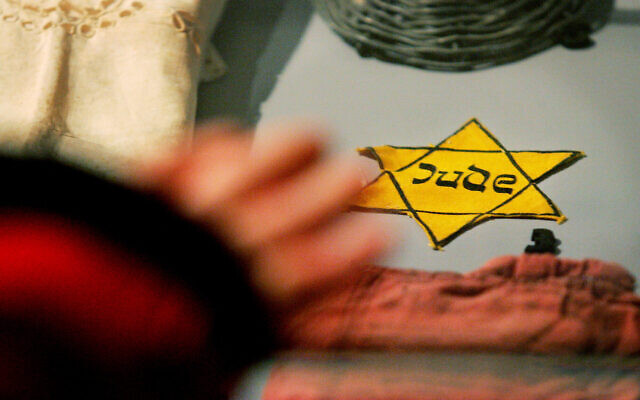 Une étoile de David jaune que les nazis obligeaient les juifs à porter, parmi d'autres objets appartenant à des survivants de la Shoah du camp de concentration d'Auschwitz-Birkenau, exposés au Mémorial de la Shoah de Yad Vashem à Jérusalem, le 24 janvier 2005 (Crédit : AP Photo/Kevin Frayer).