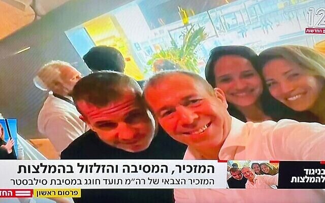 Le secrétaire militaire du gouvernement Avi Gil (à droite) pose pour un selfie avec le porte-parole de NSO Oded Hershkovitz lors d'une fête du Nouvel An à Tel Aviv. (Capture d'écran de Channel 12)