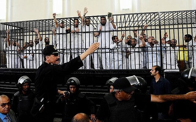 Illustration : Les partisans des Frères musulmans et d'autres islamistes font des gestes depuis la cage des accusés alors qu'ils reçoivent des sentences dans un procès de masse à Alexandrie, en Égypte, le 19 mai 2014. (AP Photo/Heba Khamis)