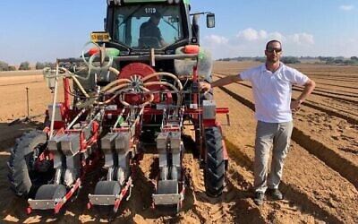 Dotan Borenstein, PDG de SaliCrop, se tient à côté d'un tracteur distribuant des graines de carotte pour un essai en plein champ près de la frontière de Gaza, le 23 août 2020. (Courtoisie)