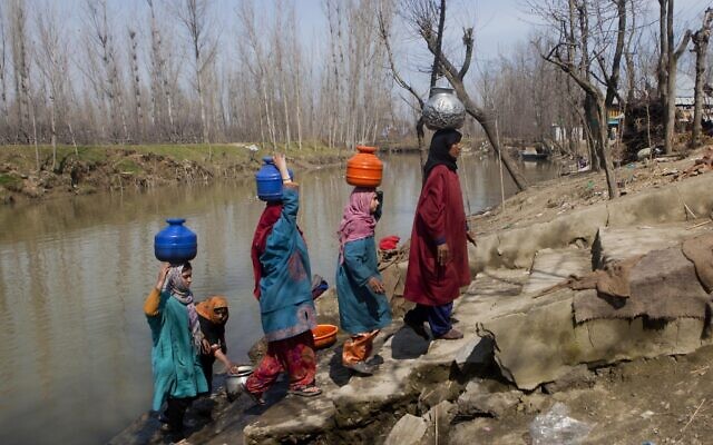 Des femmes transportent des récipients d'eau après les avoir remplis dans une rivière polluée à Khuniphat,à environ 30 kilomètres au nord de Srinagar, dans la partie du Cachemire contrôlée par l'Inde, le 21 mars 2015. (Crédit : AP Photo/Dar Yasin/File)