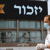 Illustration : Un homme portant un masque et un équipement de protection se tient près d'une bannière représentant une étoile de David jaune datant de l'Holocauste, à Tel Aviv, le 21 avril 2020. (Jack Guez/AFP via Getty Images)