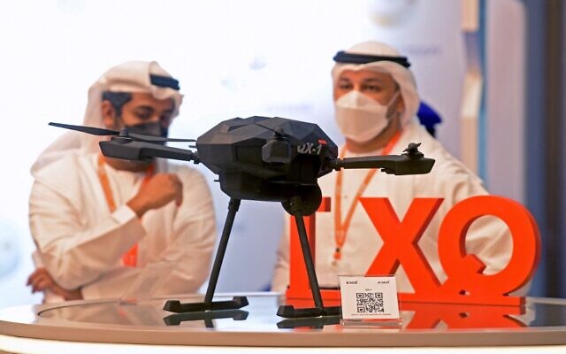 Des visiteurs se tiennent près d'une maquette d'un drone kamikaze QX-1 à munitions flottantes par par EDGE à l'exposition UMEX qui présente des drones, de la robotique et des systèmes sans pilote au Centre national des expositions d'Abu Dhabi, dans l'émirat du Golfe, le 22 février 2022. (Crédit : AFP)