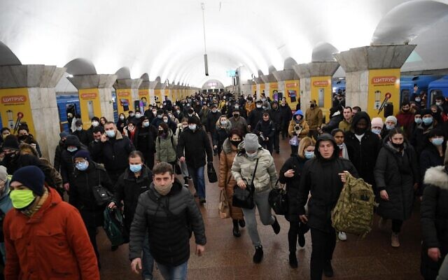 Des personnes, certaines portant des sacs et des valises, marchent dans une station de métro à Kiev, tôt le 24 février 2022. (Crédit : Daniel LEAL / AFP)