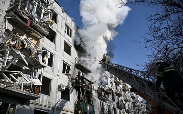 Les pompiers travaillent sur un incendie dans un bâtiment qui a été bombardé par la Russie dans la ville de Chuguiv, dans l'est de l'Ukraine, le 24 février 2022. (Aris Messinis/AFP)