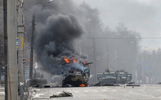 Cette photo prise le 27 février 2022 montre un véhicule blindé de transport de troupes russe brûlant à côté du corps d'un soldat non identifié lors d'un combat avec les forces armées ukrainiennes à Kharkiv. Les forces ukrainiennes ont gardé le contrôle total de Kharkiv le 27 février 2022 à la suite de combats de rue avec les troupes russes dans la deuxième plus grande ville du pays, a déclaré le gouverneur local. (Crédit : Sergueï BOBOK / AFP)