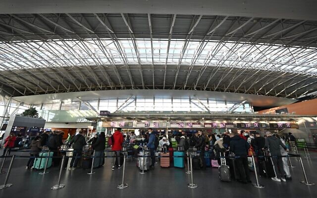 Des voyageurs attendent aux comptoirs d'enregistrement avant leur vol à l'aéroport de Boryspil, à une trentaine de kilomètres de Kiev, le 13 février 2022. (Sergei Supinsky / AFP)